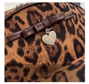 Détail de sac à dos en velours léopard avec noeud en cuir et pendentif coeur
