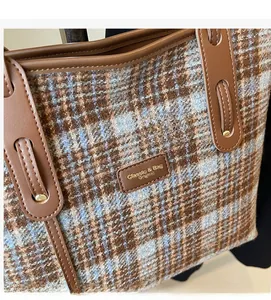 Gros plan d'un sac cabas en laine à carreaux avec garniture en cuir brun et rivets dorés