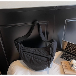 Dettaglio borsa dumpling in nylon nero con tirante intrecciato e tracolla larga