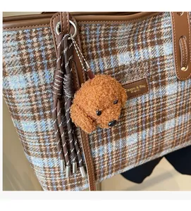 Gros plan du charme de chien en peluche marron sur un sac cabas à carreaux bleu