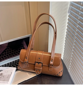Detail of retro brown leather shoulder bag with silver buckles and rivets on desk