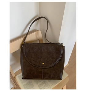 Détail du sac cabas en similicuir marron foncé avec bouton doré sur une chaise