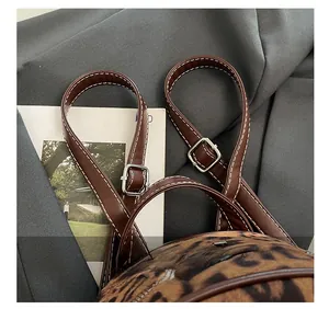 Détail gros plan de la bandoulière réglable en cuir sur un sac à dos imprimé léopard