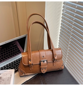 Detail of vintage brown shoulder bag with shiny PU leather, buckle and metal rivets