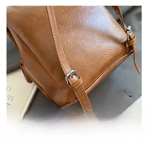 Detail view of the brown vintage backpack showing adjustable shoulder strap with silver buckle