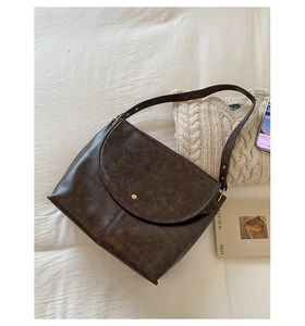 Détail du grand sac cabas rétro marron foncé sur du linge blanc avec des accessoires