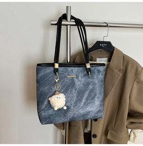 Detail of grey tote bag with marble texture, golden hardware and a cute sheep charm