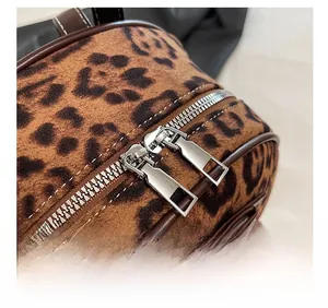 Détail de double fermeture éclair argentée sur sac à dos en velours léopard avec bord brun