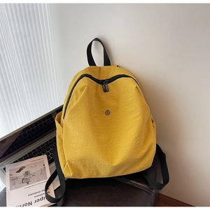 Dettaglio dello zaino in nylon giallo brillante con cerniera nera su sedia