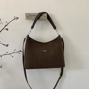 Detailed view of the brown suede hobo bag with adjustable strap and logo patch