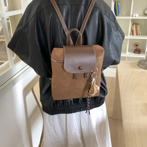 Dettaglio dello zaino vintage in pelle scamosciata marrone con patta in pelle e ciondolo