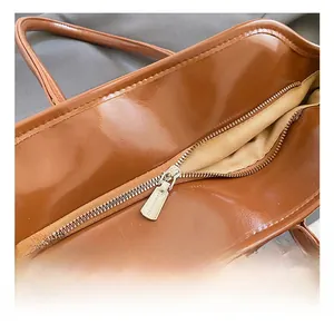 Detailaufnahme des Metall-Reißverschlusses an der braunen Shopper-Tasche aus glänzendem Leder