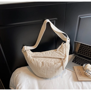 Dettaglio della borsa a mezzaluna beige con tracolla regolabile e tessuto testurizzato