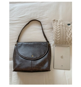 Détail du cabas en cuir marron vintage avec boucle dorée posé près d'un iPad