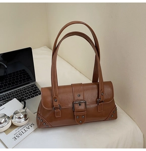 Detail of vintage brown baguette bag featuring glossy texture and metal buckle accents