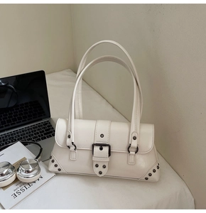 Detail of cream white faux leather shoulder bag with vintage rivets and buckle strap