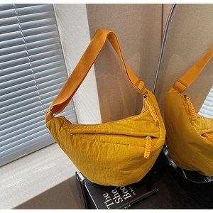 Dettaglio di una borsa a tracolla a mezzaluna in nylon giallo con tracolla in tessuto e zip