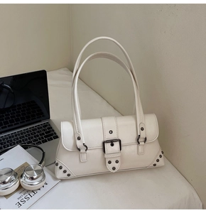 Detail of white vintage underarm bag with metal buckle and rivets on white surface