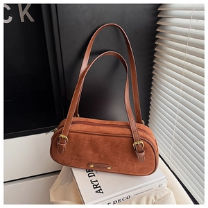 Detail of a brown suede Boston bag showing the adjustable strap and metal logo plate