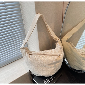 Vista dettagliata della borsa a mezzaluna beige con trama e tracolla regolabile