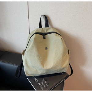 Dettaglio zaino in nylon verde chiaro su divano in pelle con tessuto resistente e zip