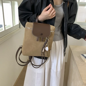 Dettaglio di uno zaino vintage opaco bicolore con texture scamosciata e charm sportivo