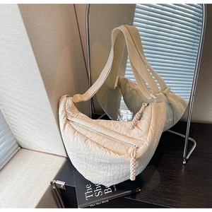 Dettaglio borsa a mezzaluna trapuntata beige con doppia zip e tiranti intrecciati