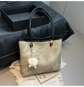 Detail of large tote bag in coffee synthetic leather with black straps and sheep pendant