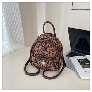 Détail du mini sac à dos à imprimé léopard avec nœud marron et pendentif en cœur argenté