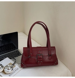 Detail of dark red vintage faux leather handbag with large metal buckle and silver studs
