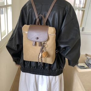 Dettaglio zaino vintage in pelle scamosciata opaca con patta marrone e ciondolo intrecciato
