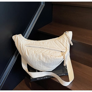 Dettaglio della borsa a mezzaluna beige con trama in nylon plissettato su scale
