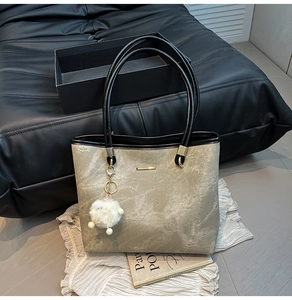 Detail of khaki marble texture tote bag with gold metal trim and cute sheep charm