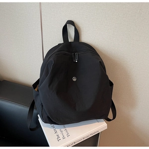 Dettaglio zaino in nylon nero con logo argentato e chiusura lampo a doppia via