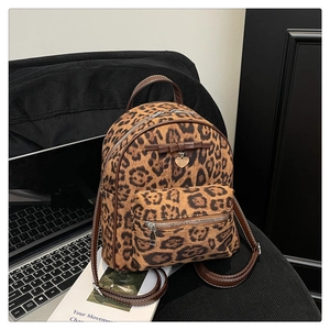 Détail du mini sac à dos léopard avec nœud marron, breloque cœur et poche zippée