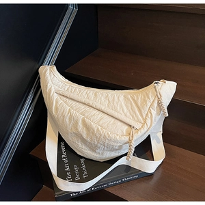 Dettaglio della borsa a mezzaluna bianco panna con trama a pieghe e cerniera in corda