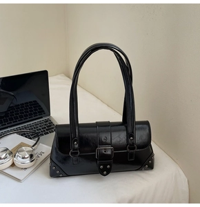 Close-up of black vintage underarm bag featuring silver rivets and metal buckle closure