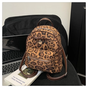 Détail du mini sac à dos léopard avec bordure en cuir marron et pendentif cœur