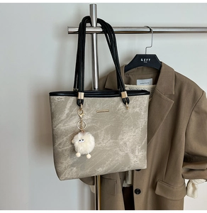 Detail view of khaki textured tote bag with black handles and cute lamb pendant