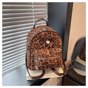 Détail du mini sac à dos en velours léopard avec nœud brun et pendentif en cœur