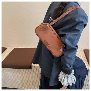 Detailed side view of a brown vintage Boston bag paired with a dark navy blazer