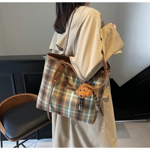Detail of vintage wool plaid tote bag with brown leather handles and puppy charm