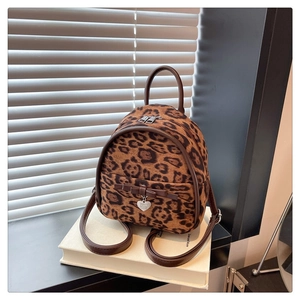 Détail d'un sac à dos en velours léopard avec pendentif cœur et nœud élégant