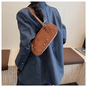 Close-up of brown suede baguette bag featuring adjustable strap and gold metal buckle