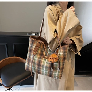 Détail du sac cabas en laine à carreaux avec anses en cuir et charmant pendentif chien
