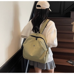 Vista posteriore di uno zaino casual in tela verde chiaro indossato da una modella