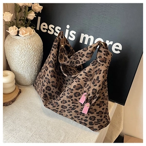 Detail of leopard print tote bag with pink leather hooks and textured fabric finish