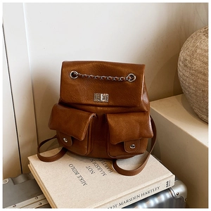 Detail of vintage brown leather backpack showing metal chain decor and silver twist lock