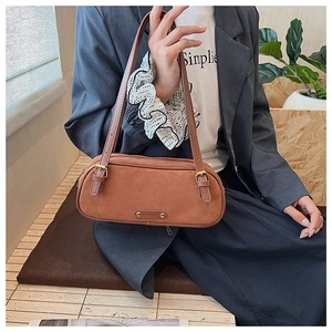 Brown suede Boston bag with dual leather shoulder straps shown on a grey blazer outfit
