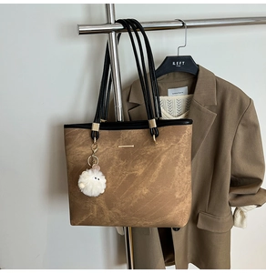 Close-up of brown marble-textured tote bag with black straps and cute sheep pendant